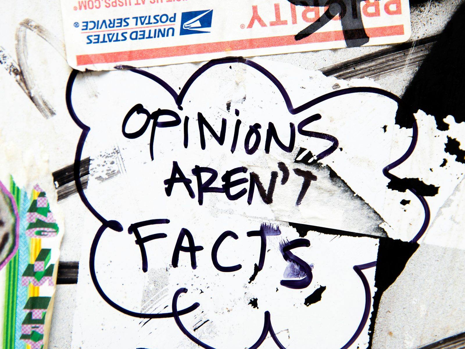 Street art reading "Opinions Aren't Facts" pasted on a wall