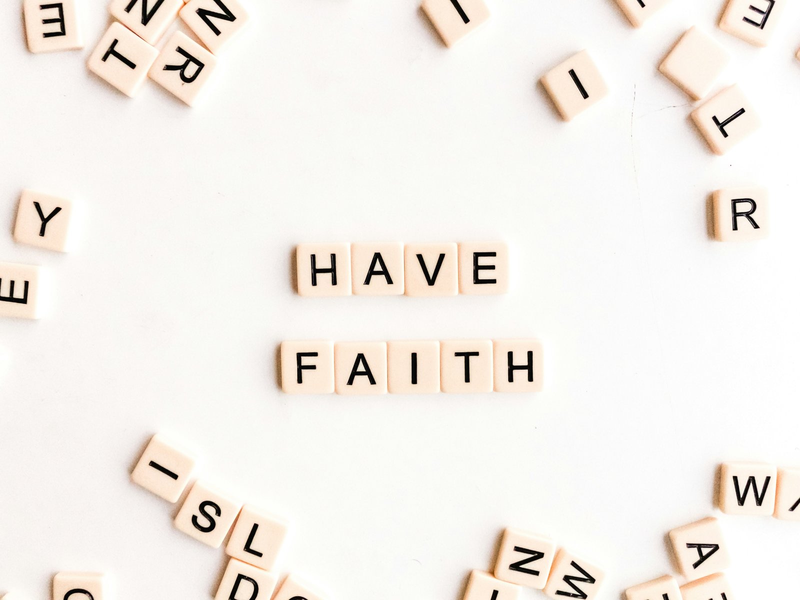 Wooden letter tiles spelling HAVE FAITH at the center of scattered single letters, each piece meaningless alone and useful only alongside the others, like departments that need each other