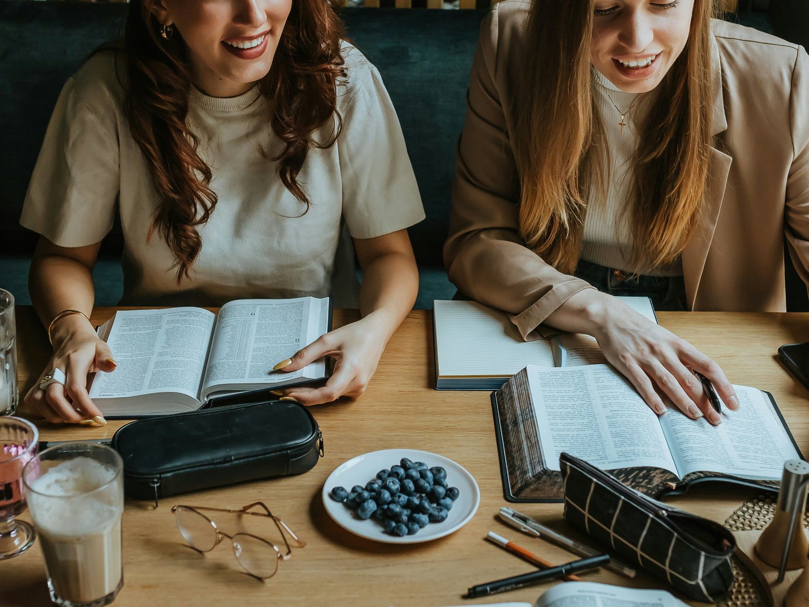 A small group of colleagues gathered around a table with open Bibles and notebooks, studying together