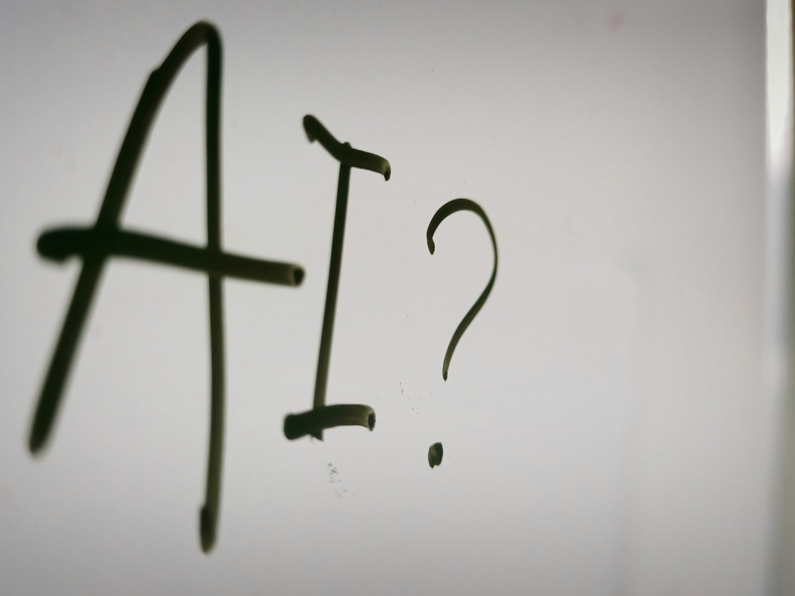 The letters "AI?" hand-drawn in black marker on a white board, the question owners face when AI starts changing the jobs on their team